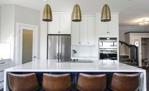 cozinha com moveis brancos e cadeiras marrons