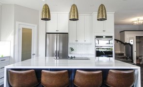 cozinha com moveis brancos e cadeiras marrons